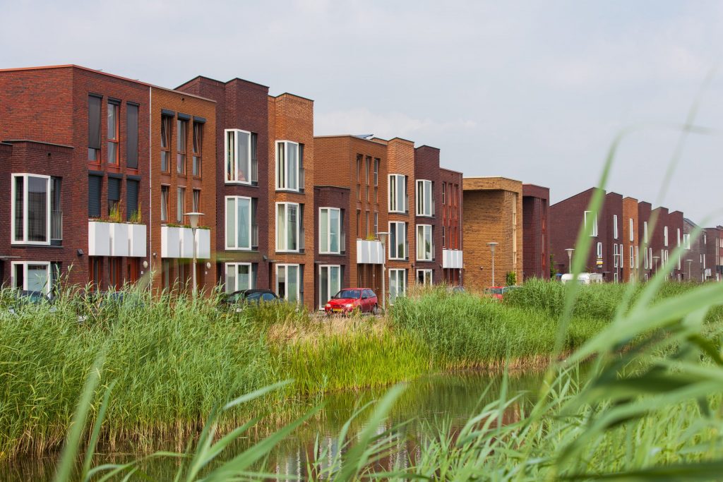 Een rij met nieuwbouwhuizen en een sloot op de voorgrond